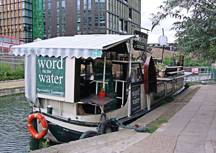Libreria galleggiante ormeggiata lungo un canale, che offre un'esperienza di biblioteca accogliente e magica sull'acqua.