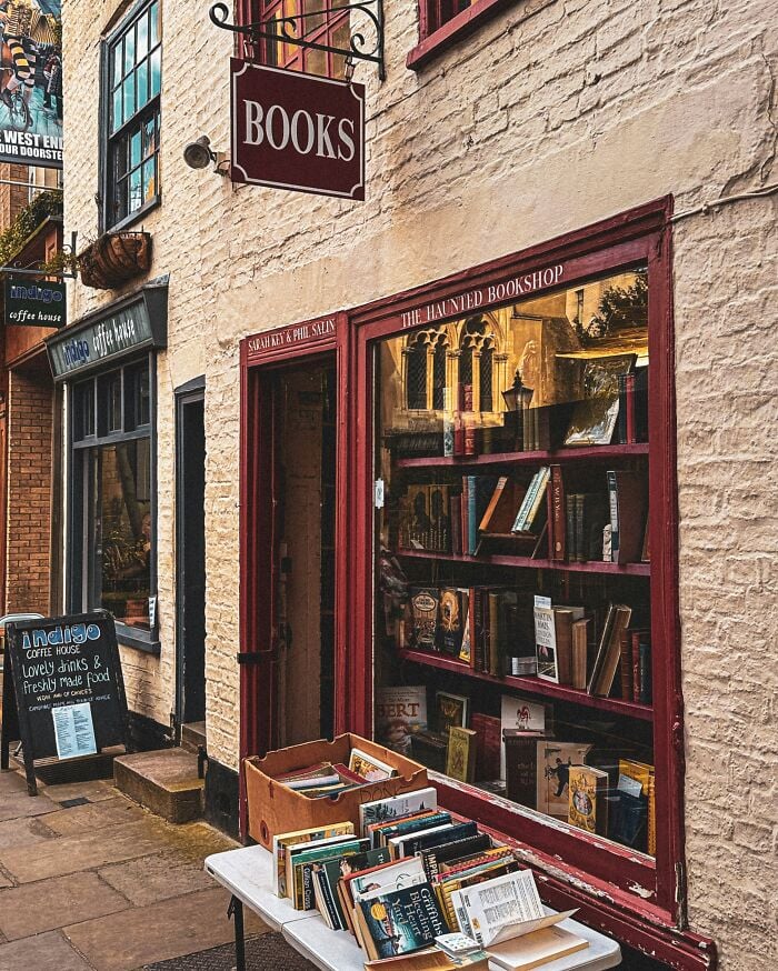 Libreria accogliente e grandiosa con libri esposti all'esterno, caratterizzata da una facciata affascinante e un'atmosfera calda e invitante.
